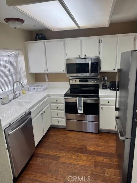 kitchen with light countertops, appliances with stainless steel finishes, a sink, and white cabinets