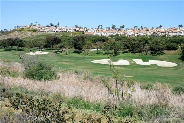 view of property's community featuring view of golf course and a yard