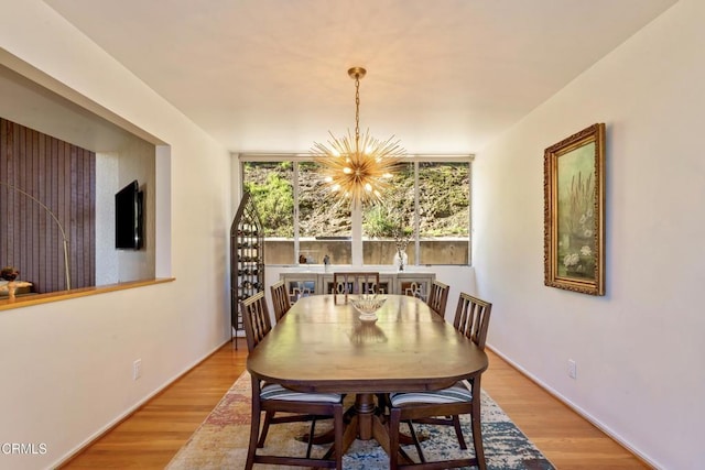 dining area with wood finished floors and an inviting chandelier