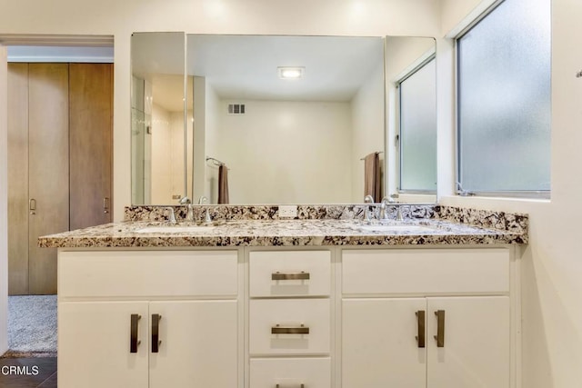 full bathroom with double vanity, visible vents, and a sink