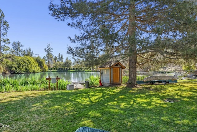 view of yard featuring a water view, a storage shed, fence, and an outdoor structure