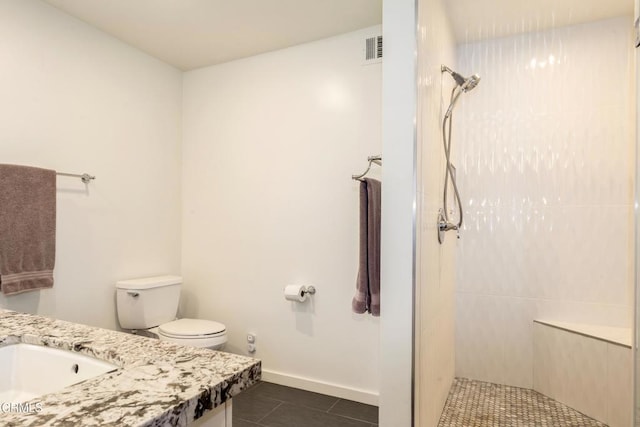 bathroom featuring baseboards, toilet, tile patterned floors, vanity, and a walk in shower