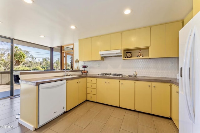 kitchen with white appliances, decorative backsplash, under cabinet range hood, open shelves, and a sink