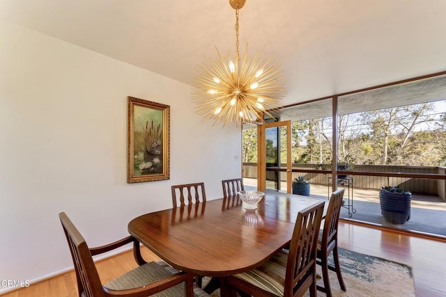 dining room featuring expansive windows, baseboards, wood finished floors, and a notable chandelier