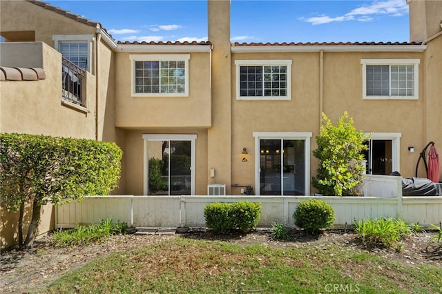 rear view of house featuring fence private yard and stucco siding