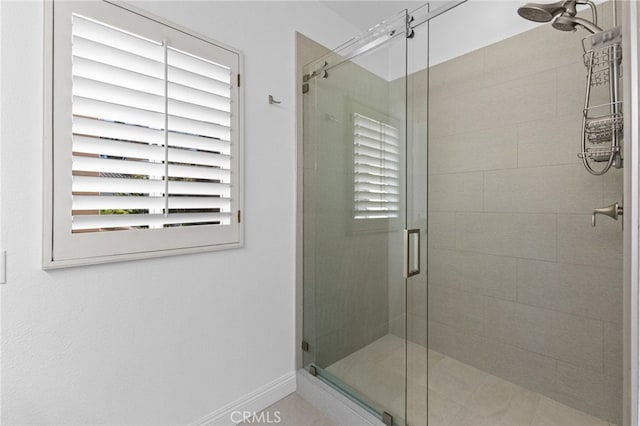 full bathroom with a shower stall and baseboards