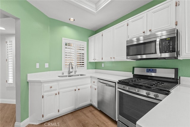 kitchen with light countertops, appliances with stainless steel finishes, a sink, and white cabinets