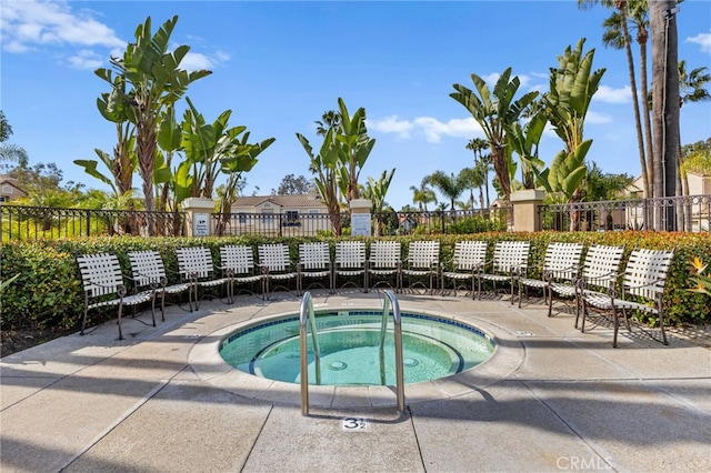 view of swimming pool featuring a community hot tub and fence