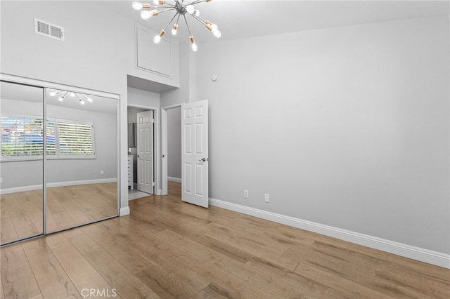 unfurnished bedroom featuring a chandelier, light wood-type flooring, visible vents, and baseboards