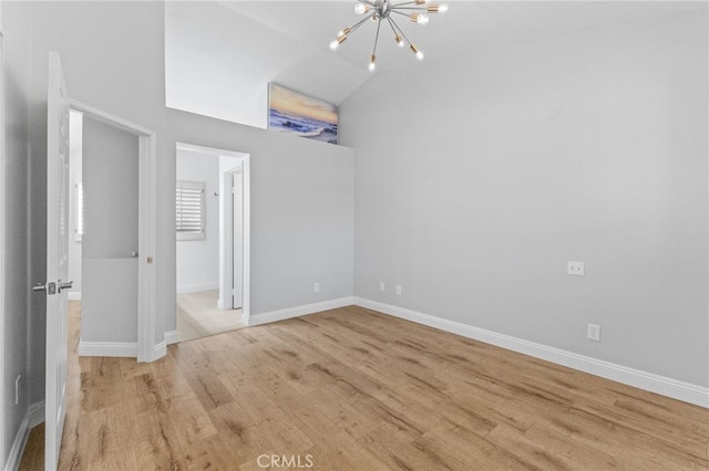 unfurnished bedroom featuring light wood-type flooring, lofted ceiling, baseboards, and an inviting chandelier