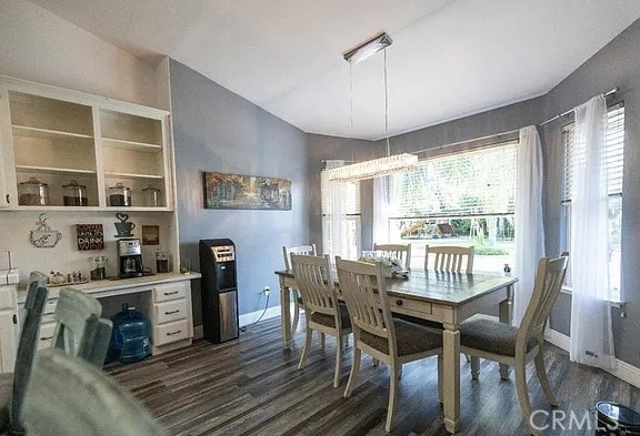 dining room with dark wood-style floors, lofted ceiling, and baseboards