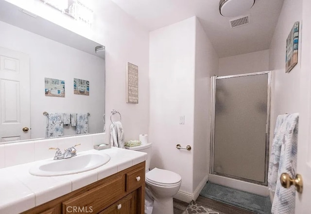 bathroom with visible vents, toilet, a shower stall, vanity, and baseboards