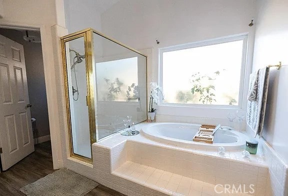 bathroom with a stall shower, wood finished floors, and a bath