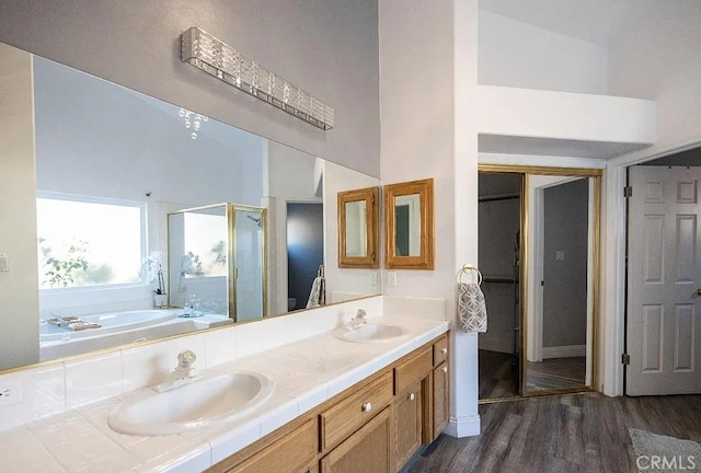 full bathroom with wood finished floors, a sink, a shower stall, and a bath