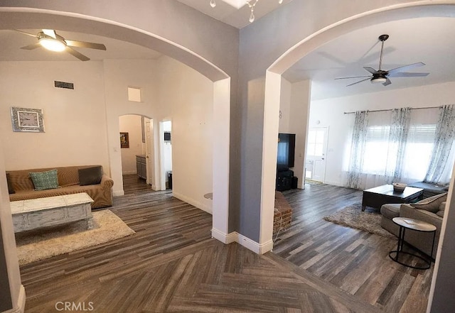 living room with arched walkways, ceiling fan, dark wood finished floors, and visible vents