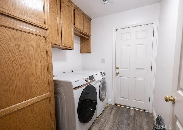 washroom with cabinet space, baseboards, visible vents, washer and clothes dryer, and dark wood-style flooring