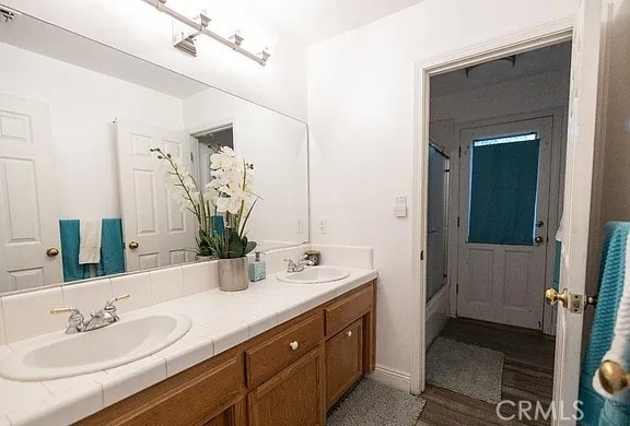 full bathroom featuring wood finished floors, a sink, and double vanity