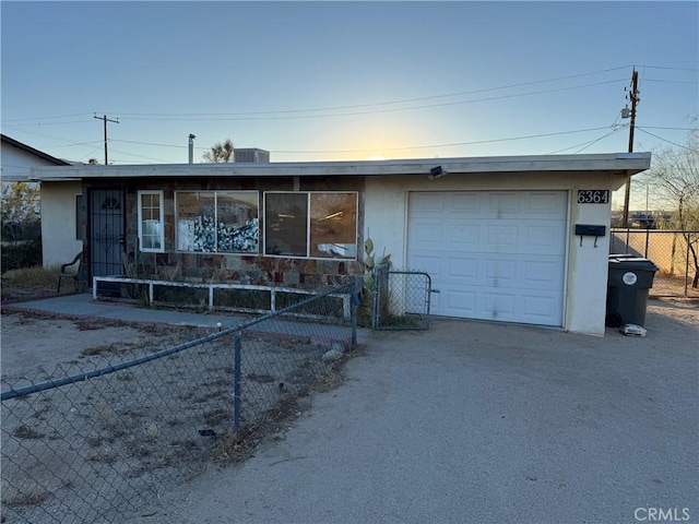 ranch-style house featuring a garage, driveway, fence, and stucco siding