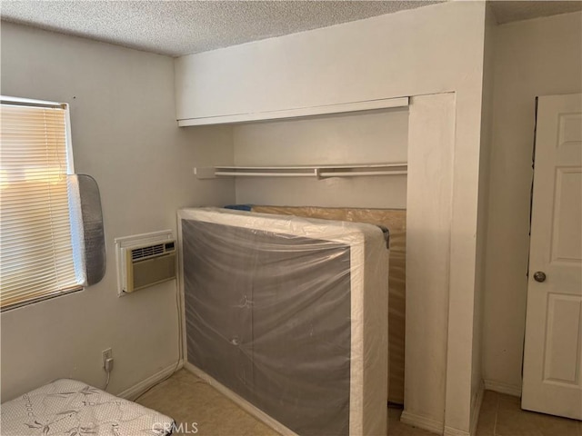 bedroom featuring a wall unit AC, baseboards, and a textured ceiling