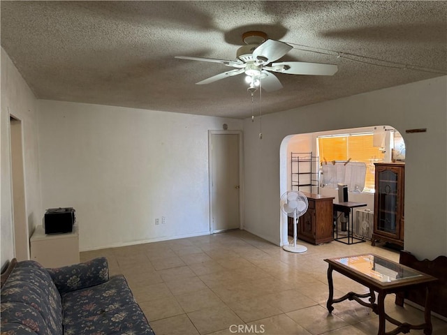 living room featuring arched walkways, ceiling fan, a textured ceiling, and light tile patterned flooring