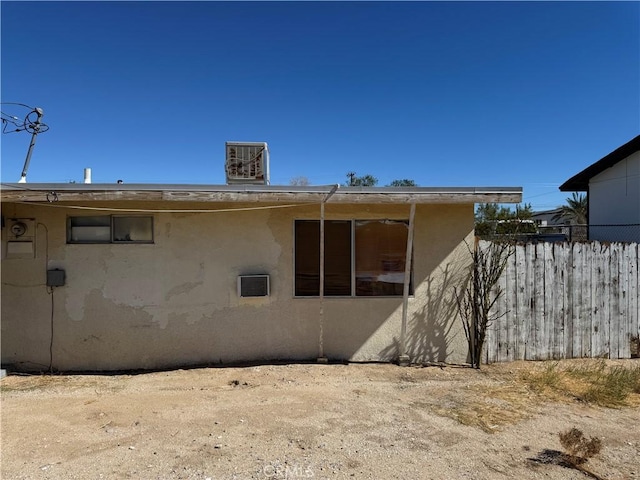 view of property exterior with central air condition unit, fence, and stucco siding