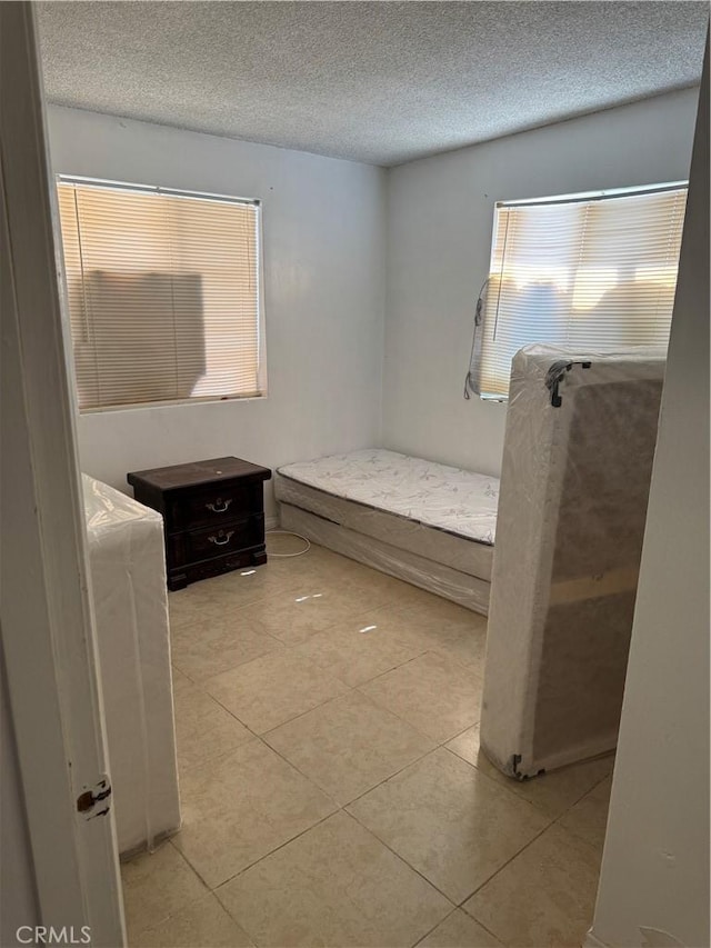 bedroom featuring a textured ceiling and light tile patterned floors