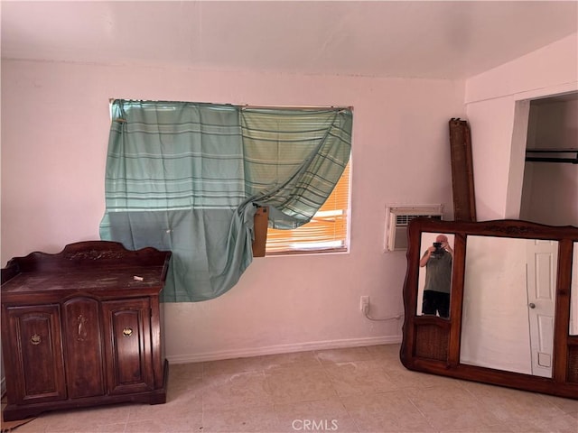 bedroom featuring a wall unit AC, baseboards, and light tile patterned floors