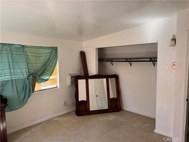 unfurnished bedroom featuring a wall mounted air conditioner and baseboards