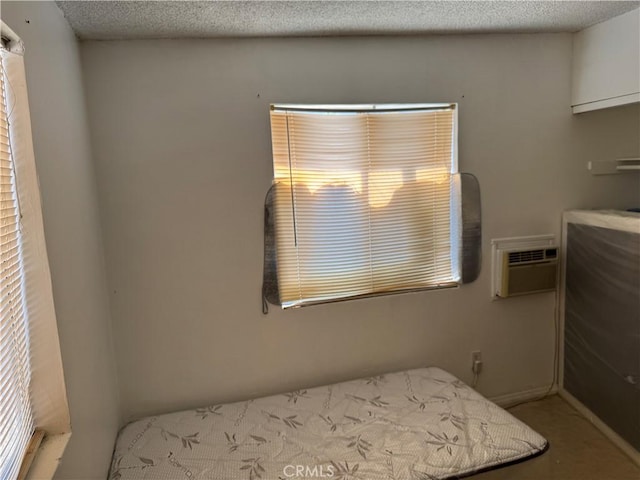 bedroom with a textured ceiling and an AC wall unit