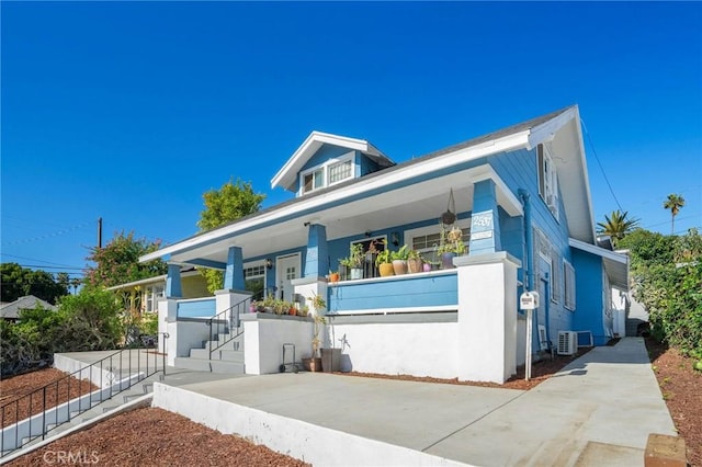 bungalow featuring a porch, cooling unit, and stucco siding