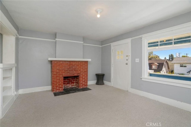 unfurnished living room with carpet floors, a brick fireplace, and baseboards