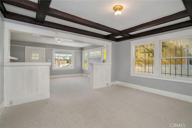 empty room featuring coffered ceiling, light colored carpet, beamed ceiling, and baseboards