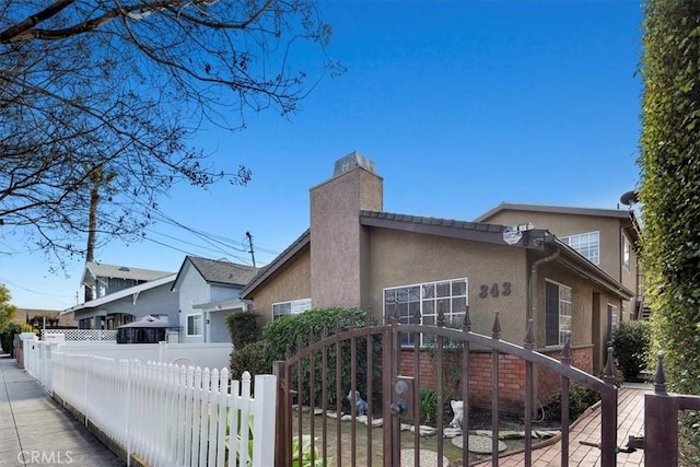 view of front facade featuring a fenced front yard, a chimney, and stucco siding