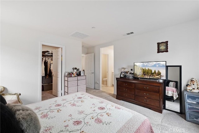bedroom featuring visible vents, ensuite bathroom, a closet, carpet floors, and a spacious closet