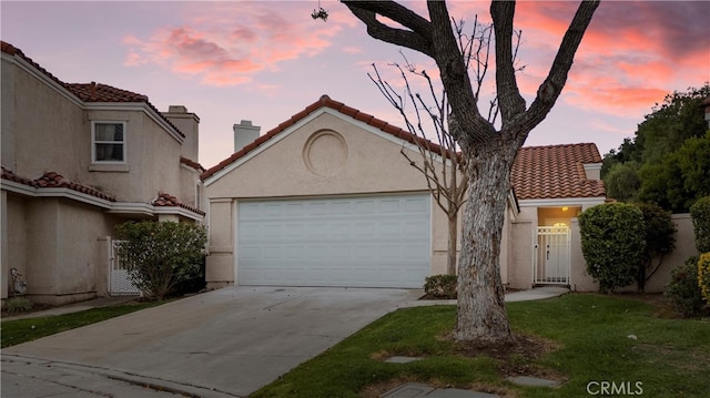 mediterranean / spanish-style house with driveway, an attached garage, a tile roof, and stucco siding