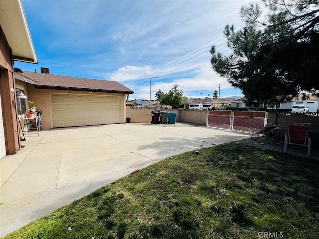 view of yard featuring fence, driveway, and an attached garage