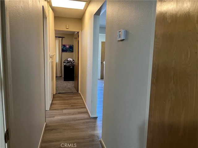 hall with baseboards and wood finished floors