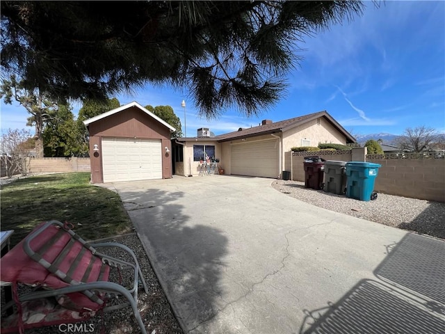 ranch-style house featuring an attached garage, fence, concrete driveway, and stucco siding