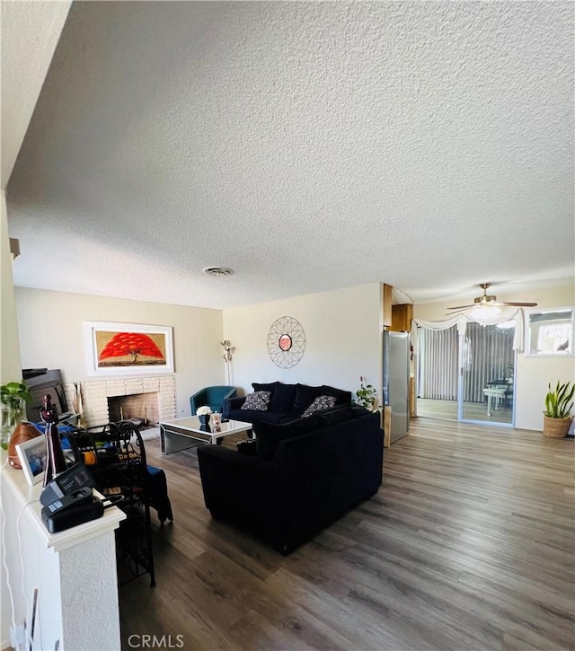 living area featuring a textured ceiling, a fireplace, wood finished floors, and visible vents