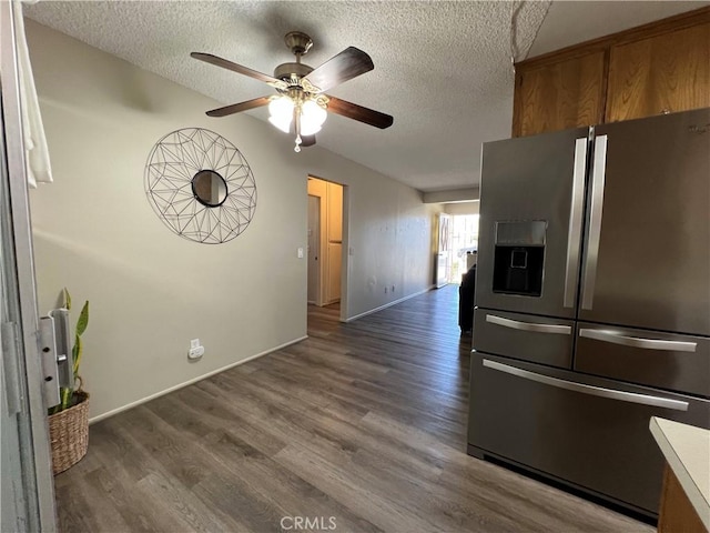 kitchen with brown cabinetry, dark wood-style flooring, stainless steel refrigerator with ice dispenser, and a textured ceiling