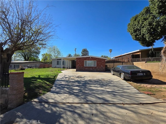 single story home featuring a front yard, concrete driveway, brick siding, and fence