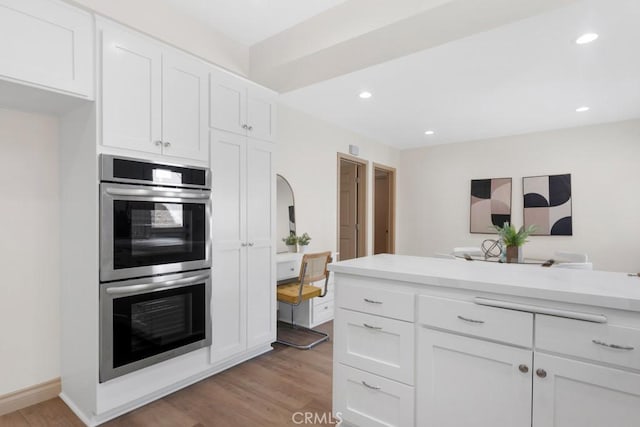 kitchen with stainless steel double oven, white cabinets, and light countertops