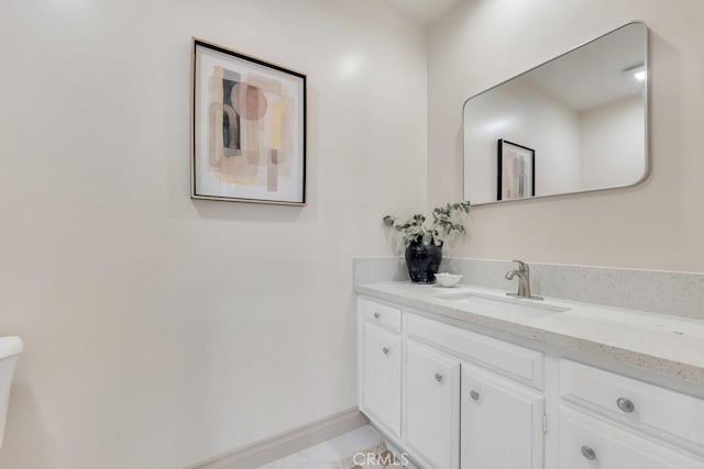 bathroom with toilet, vanity, and baseboards