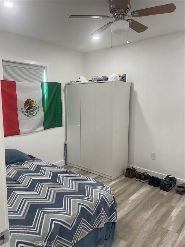 bedroom with a ceiling fan, baseboards, and wood finished floors