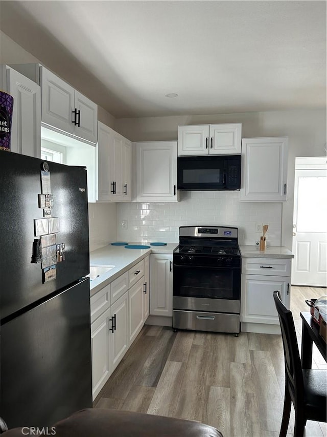 kitchen featuring black appliances, light countertops, white cabinetry, and light wood-style floors