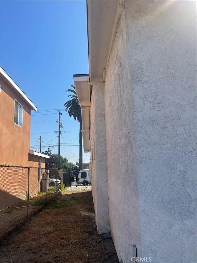 view of side of home featuring fence and stucco siding