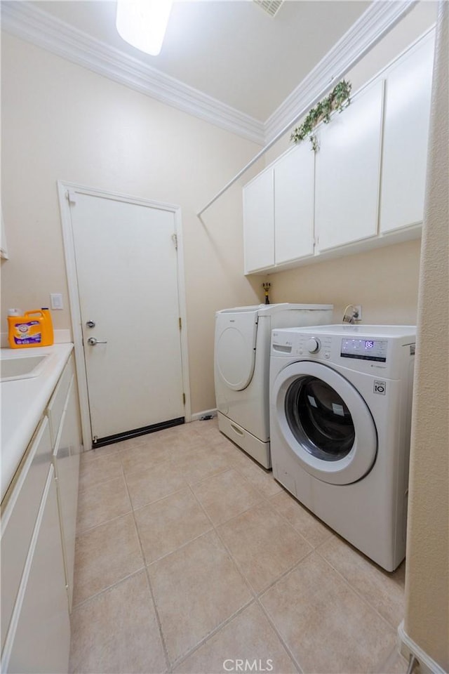 laundry area with washing machine and dryer, cabinet space, crown molding, and light tile patterned floors