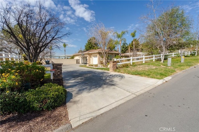 view of front of property featuring a garage, concrete driveway, and fence