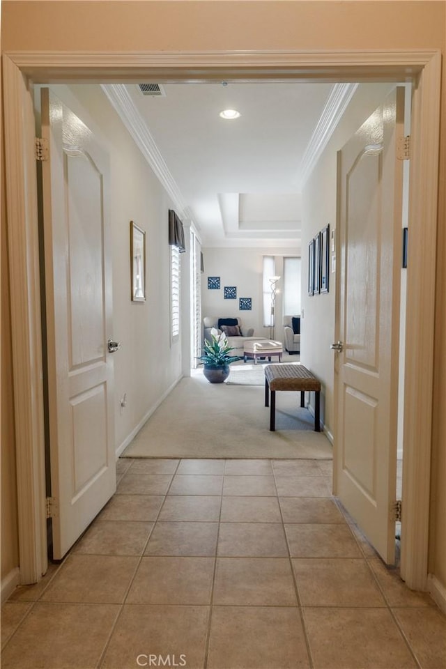 hall featuring light carpet, light tile patterned floors, ornamental molding, and a tray ceiling