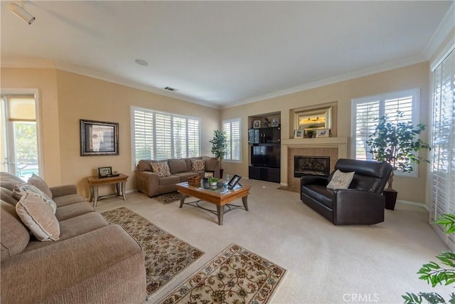 living room featuring crown molding, baseboards, a tiled fireplace, and light colored carpet